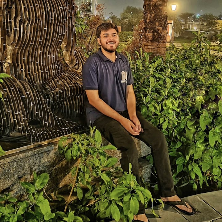 Sitting by a wooden sculpture in a garden at night